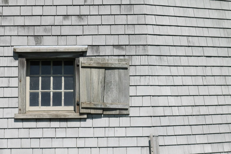 a grey building with an open window next to a door