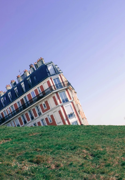 a red and white building sitting on top of a green hill