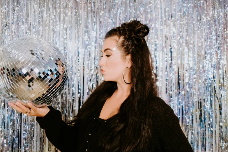 a woman holding a silver and black disco ball