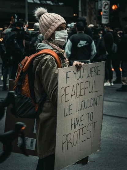 person holding sign in crowded city street with protest sign
