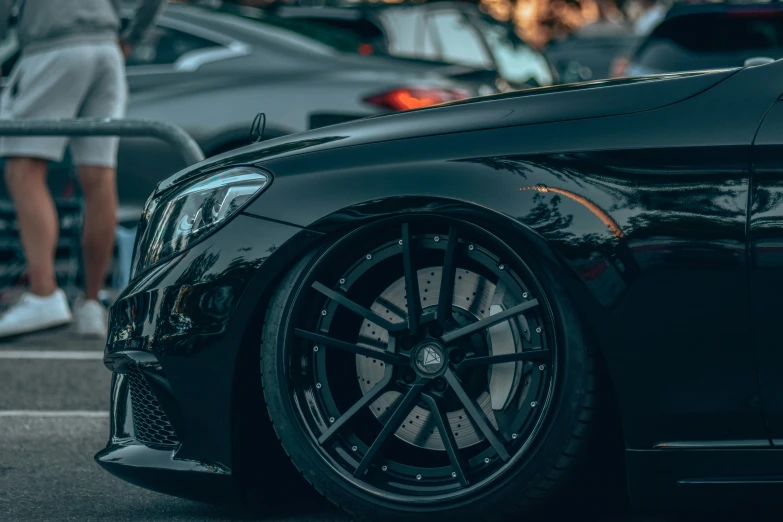 the front wheel of a black car parked in a parking lot