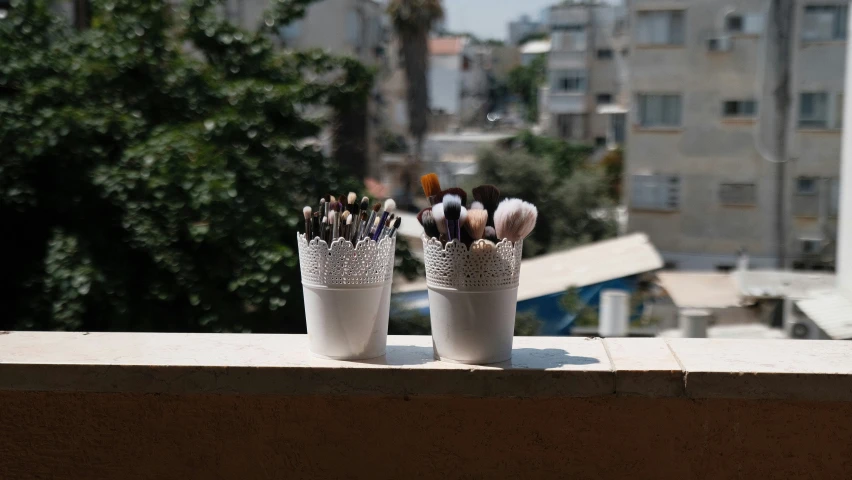 two containers holding small pens on top of a window sill