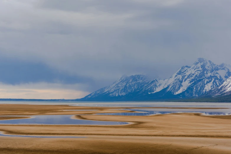 snow covered mountains are seen behind a body of water