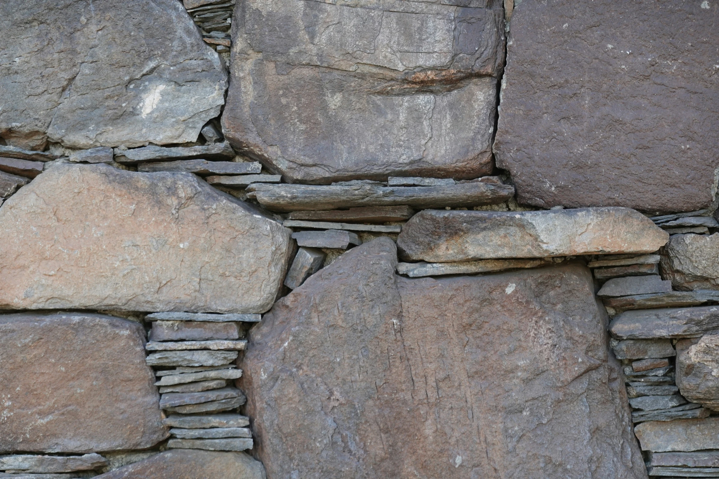 a rock wall with many large rocks and a bird on top of it