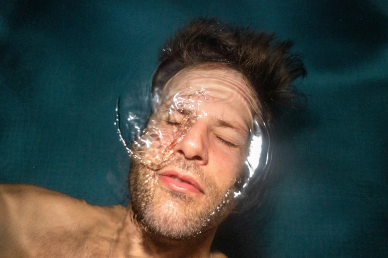 a man with a sheet on his face, half covered in water