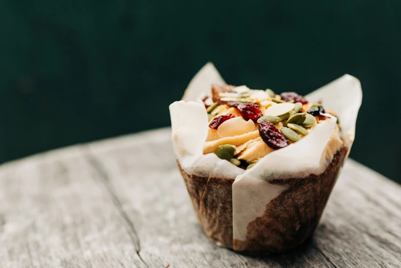 a muffin with fruit sitting on top of a wooden table