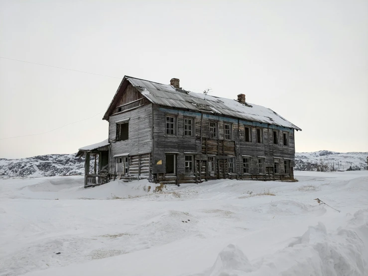 an old log house partially buried in snow