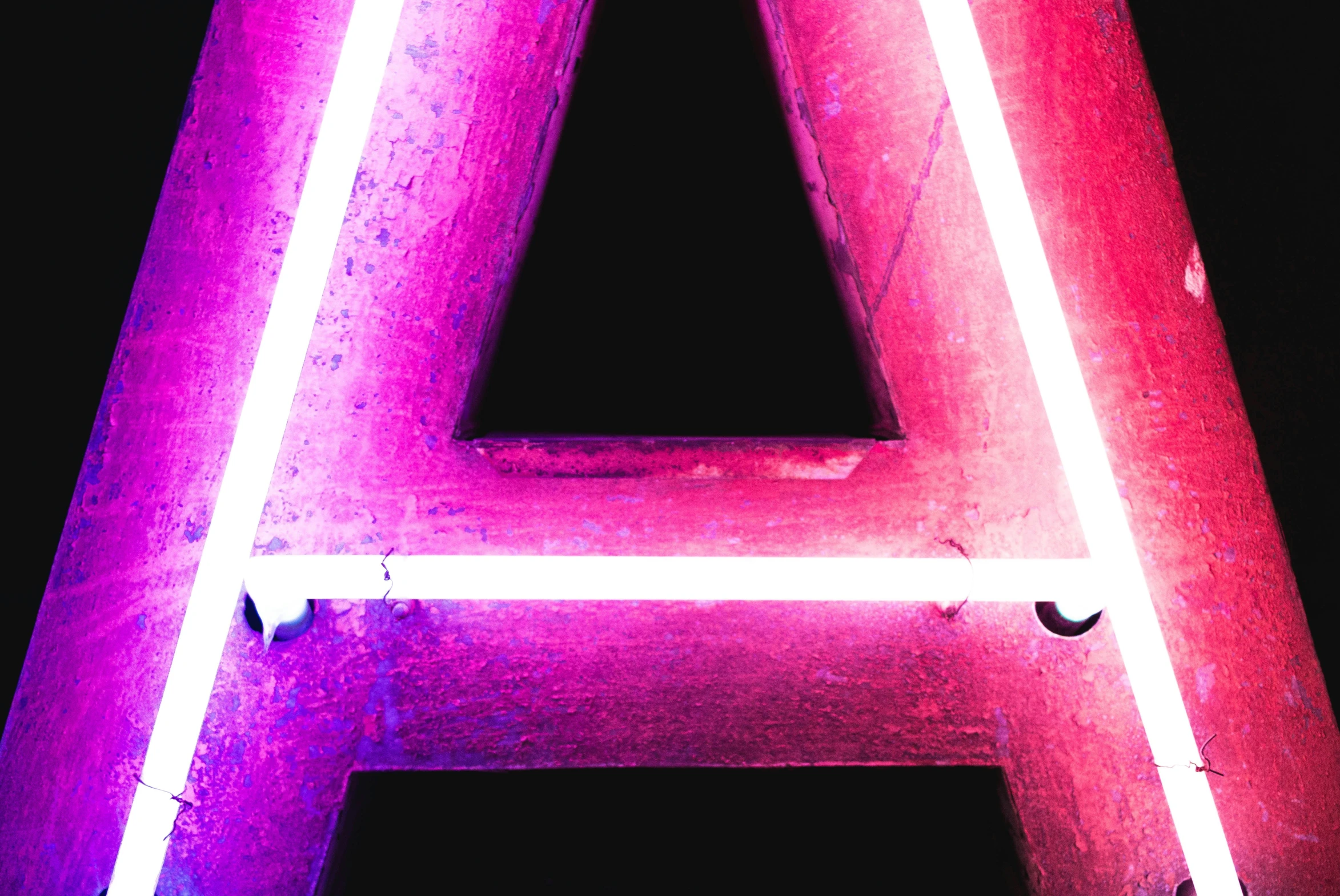 an angled sign lit up with pink and purple lights