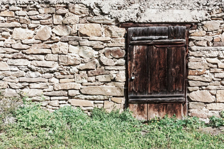 a weathered door is visible on a stone wall