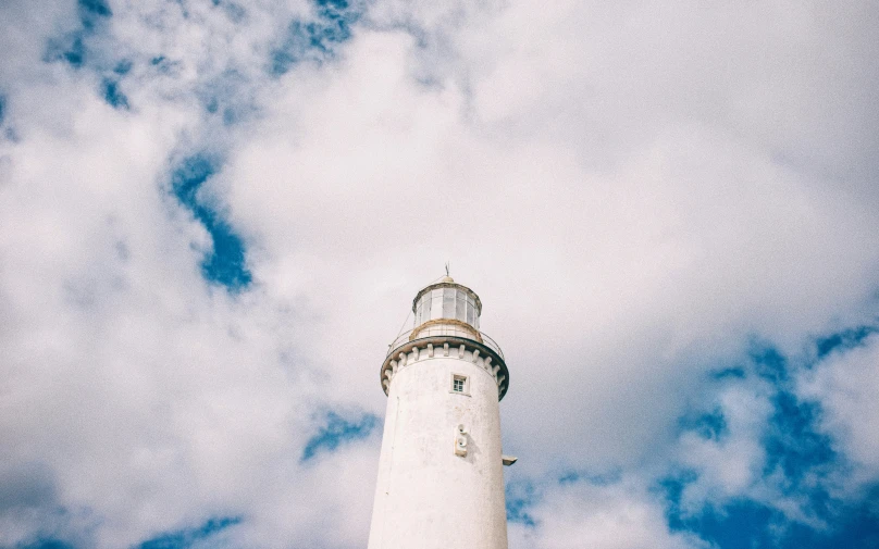 a tall white lighthouse on a partly cloudy day