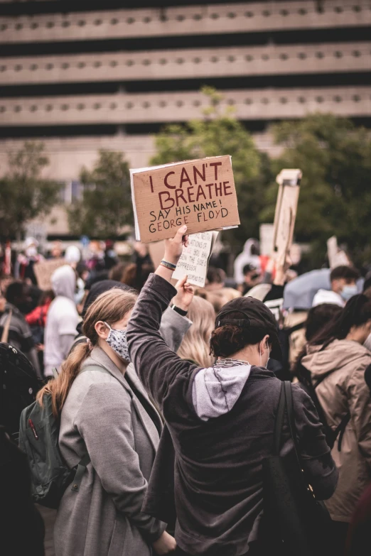 people standing on a busy sidewalk with some holding signs