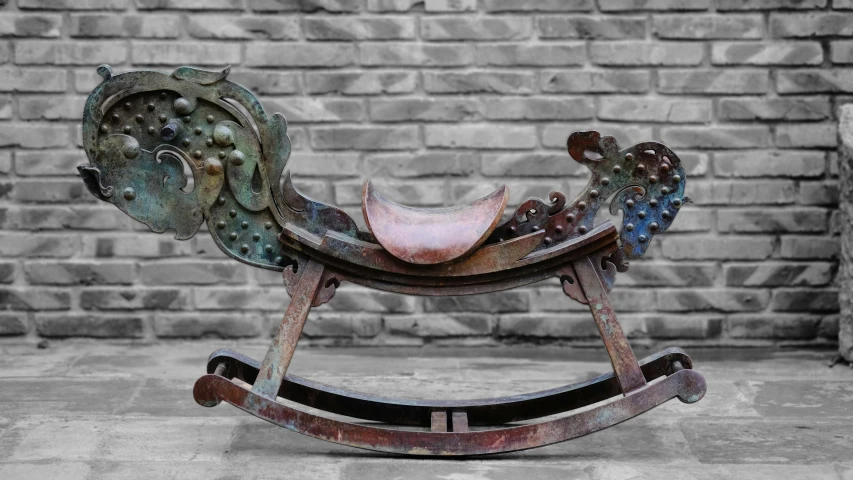 an iron rocking horse on the street by a brick wall