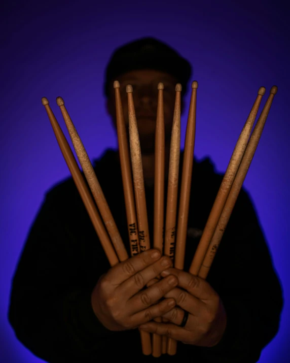 a man holding a handful of wood sticks