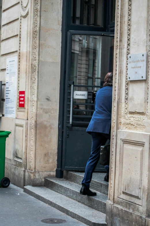 a man in business attire stepping up the side door of a building