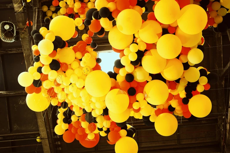 an assortment of balloons hang on a building