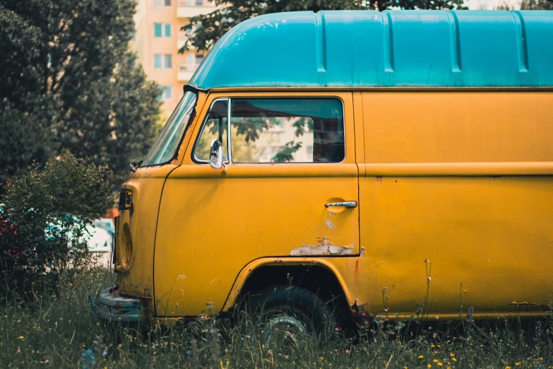 a yellow bus is parked in some grass and trees