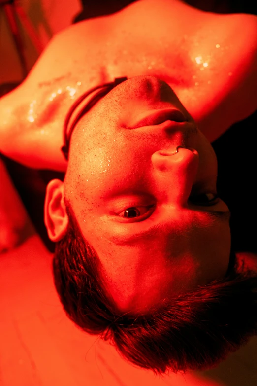 man laying on wooden floor with red light showing his chest