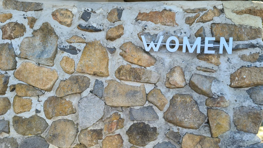 the word women spelled on the side of a stone wall