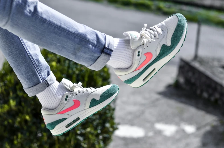 two people are sitting on a railing wearing grey and green sneakers
