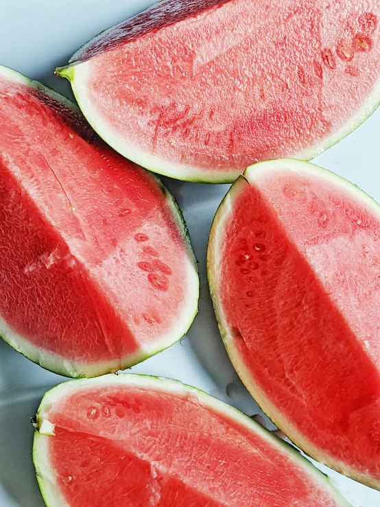 a couple of pieces of watermelon are on a white plate