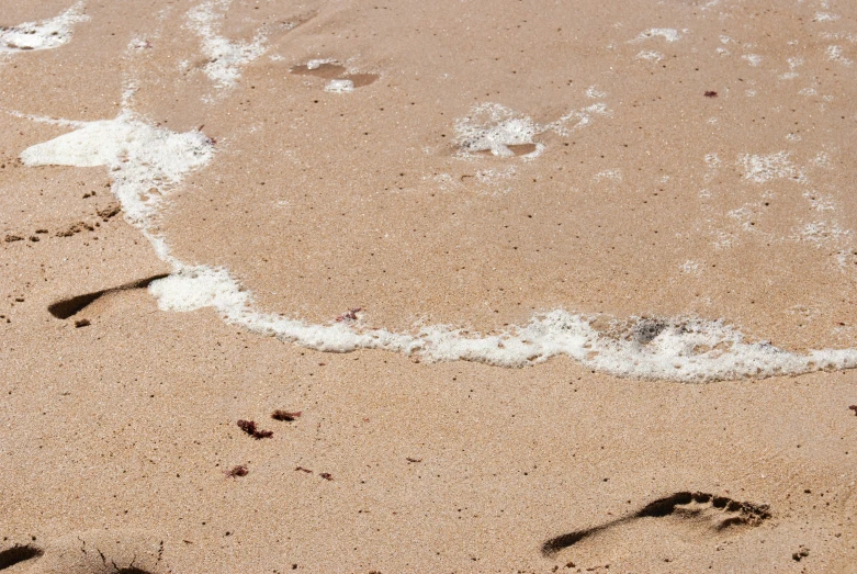 water waves coming out and leaving footprints on sand