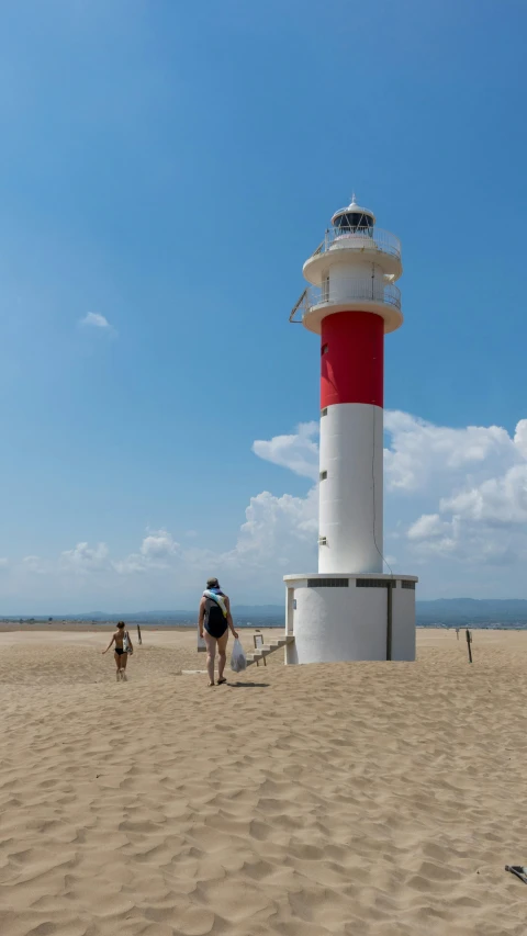 a red and white lighthouse on a sandy beach