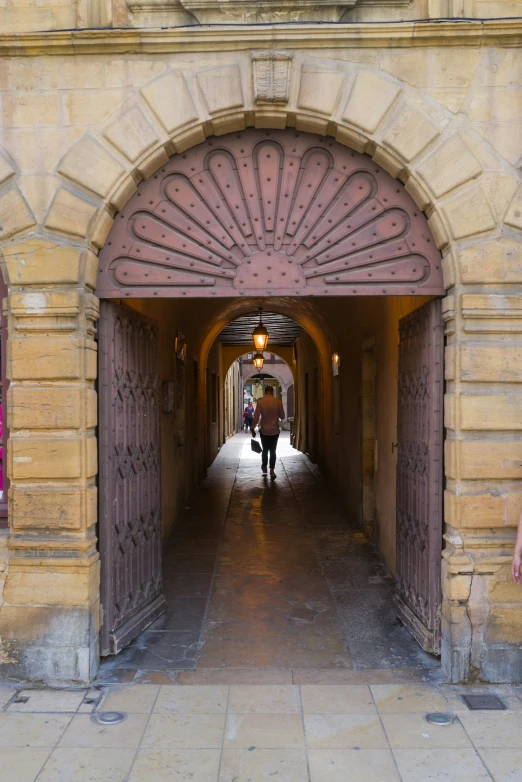 man with umbrella walking through a large, brick archway