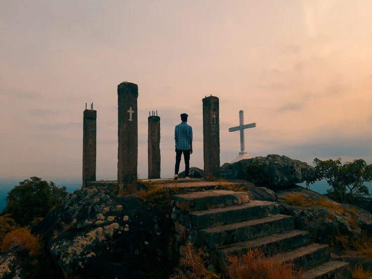 a man standing on a rock in front of two crosses