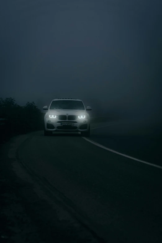 a car driving down a foggy road in the dark