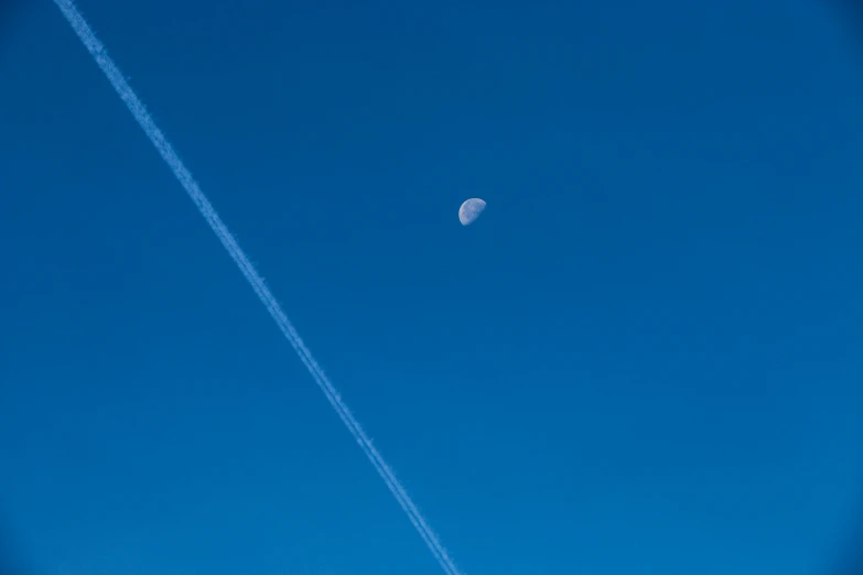 a kite in the sky and some contrails