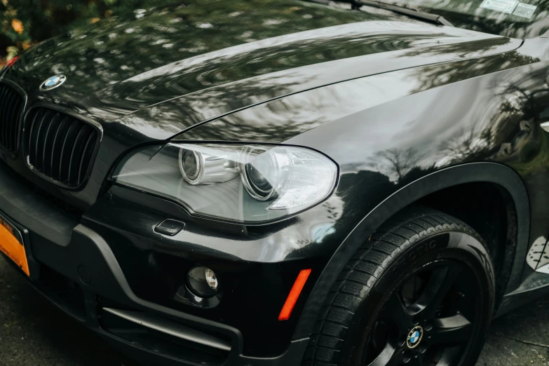 the front bumper of a black bmw parked in front of trees