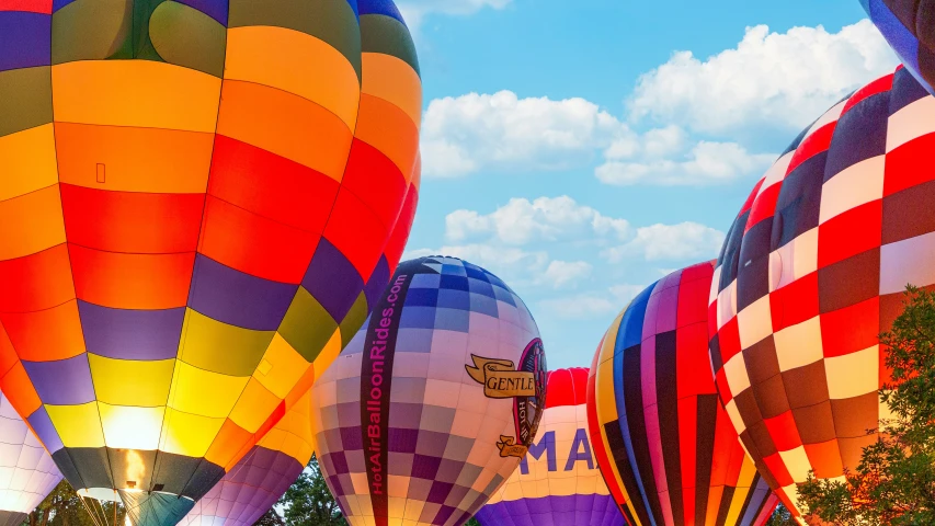 large, multicolored  air balloons are illuminated at an angle