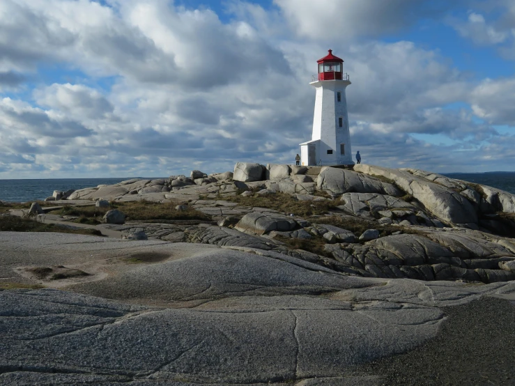 a large white and red lighthouse sitting on top of a rocky beach