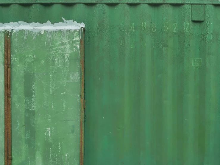 the side of a green building with snow on it