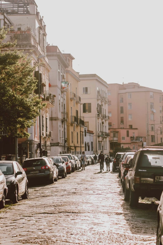 a row of parked cars and people walking down a city street