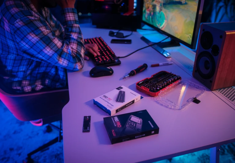 a person sitting at a computer desk with some book and other things on it