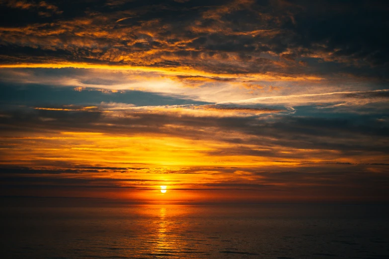 a sunset is seen over the ocean with a bright orange and blue hue