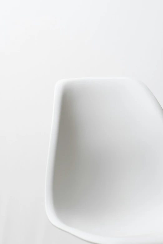 a white chair against a white wall with it's head tilted sideways