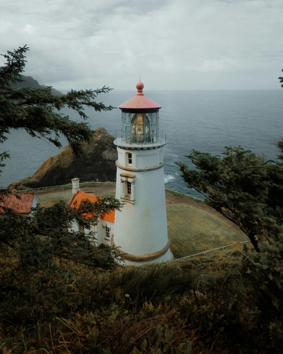 a white lighthouse on top of a hill by the ocean