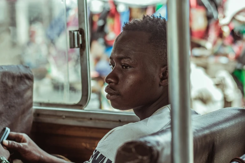 a young black man sitting down in the bus