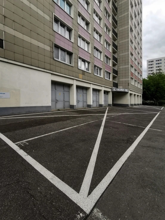 a parking lot in front of a large, brown apartment building