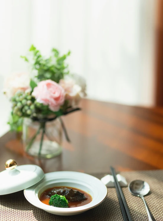 a bowl of broccoli soup is set on the table next to spoons and a spoon rest beside it