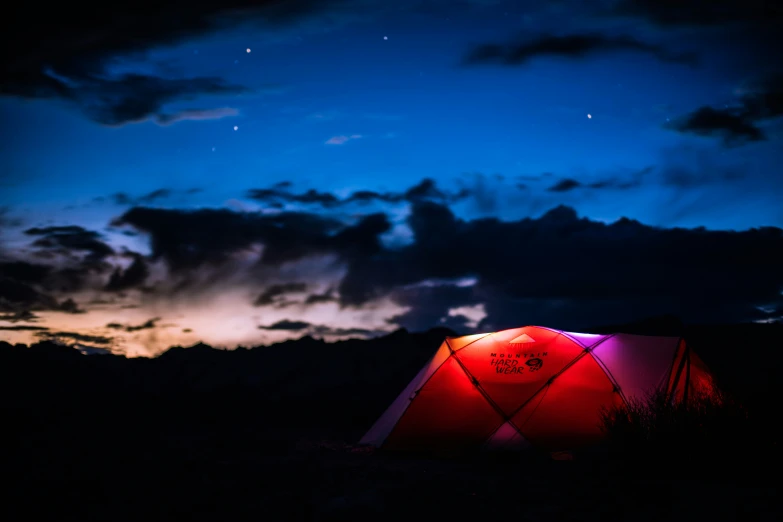 a camping tent is lit up at night
