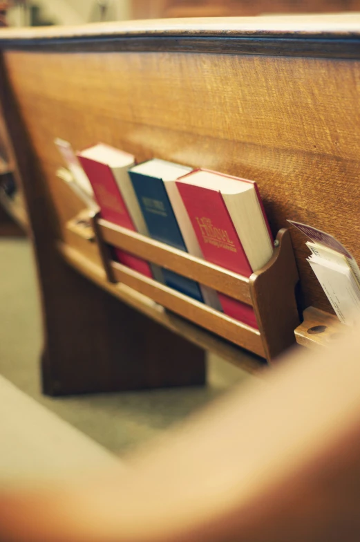 a pair of books sitting on top of a wooden church pew