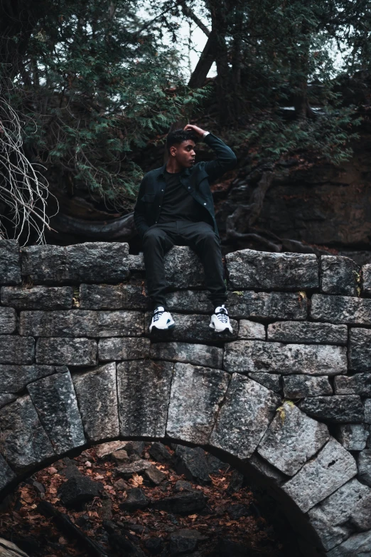 a man sitting on the side of a stone bridge