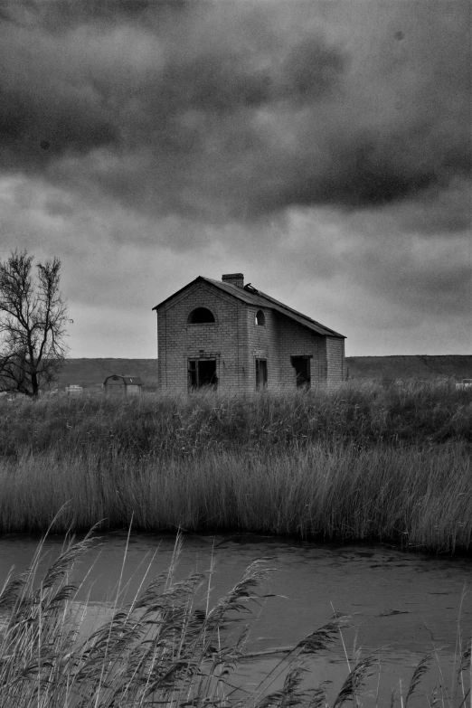 an old house sits in a field next to water