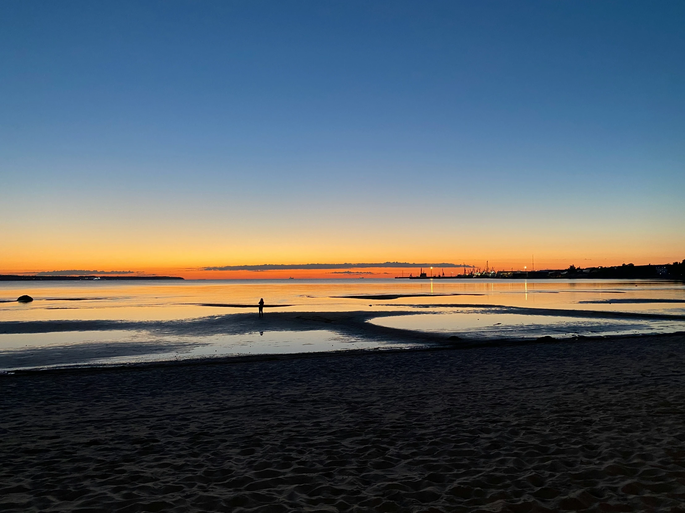 a sunset that is over the water and over sand