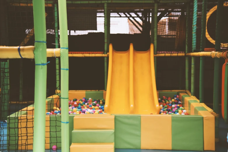 small yellow slide is next to a play wall