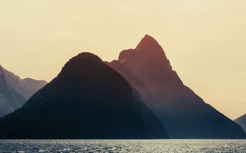 the mountains are in silhouette with water below