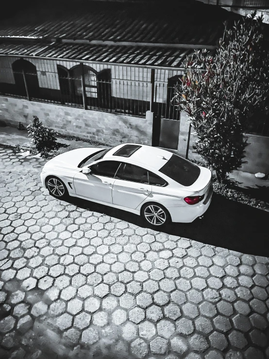 white car parked outside a building on a cobblestone area